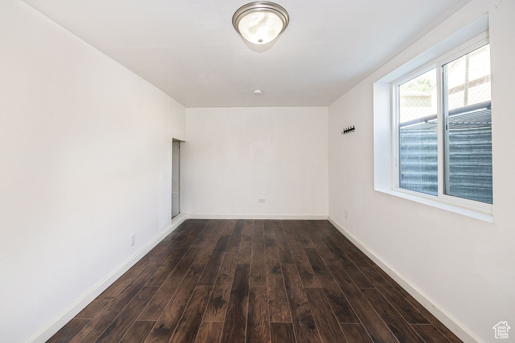 Unfurnished room with dark wood-style flooring and baseboards
