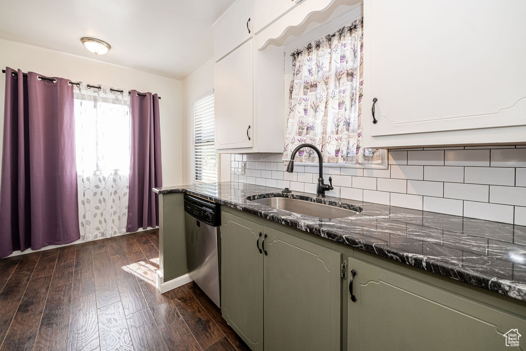 Kitchen with dishwasher, a sink, dark wood-style flooring, tasteful backsplash, and dark stone countertops