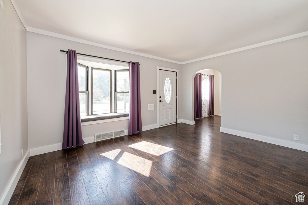 Entryway featuring arched walkways, ornamental molding, hardwood / wood-style floors, and baseboards