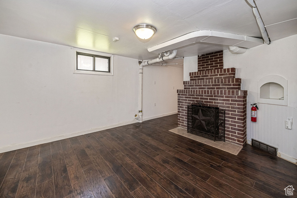 Unfurnished living room featuring a fireplace, wood finished floors, and baseboards