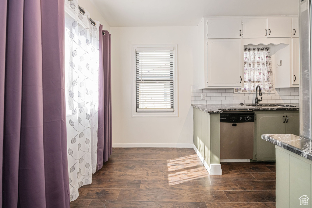 Kitchen with stainless steel dishwasher, a sink, dark wood-style flooring, and decorative backsplash