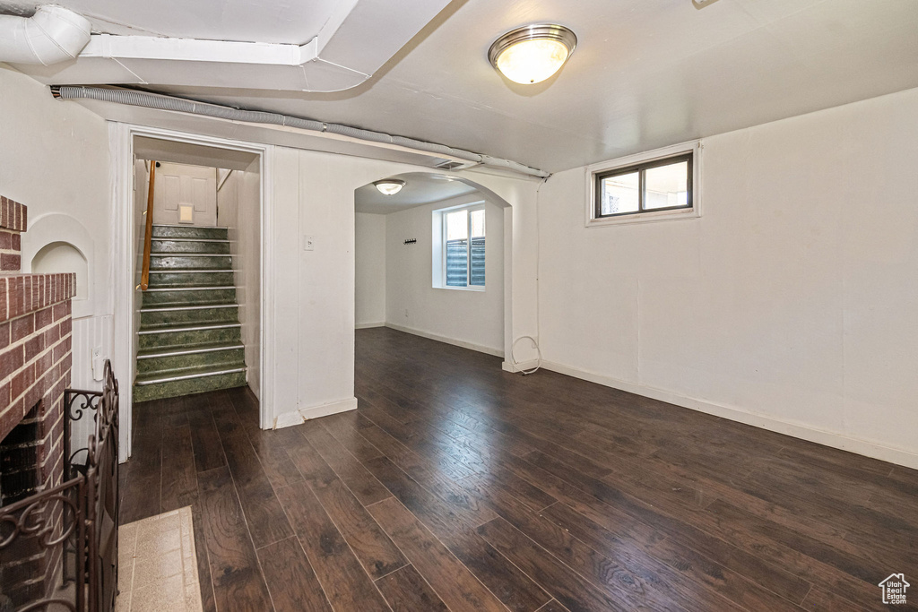 Below grade area with dark wood-style flooring, arched walkways, stairs, and baseboards