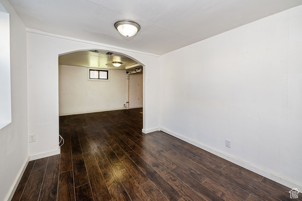 Spare room featuring arched walkways, wood finished floors, and baseboards