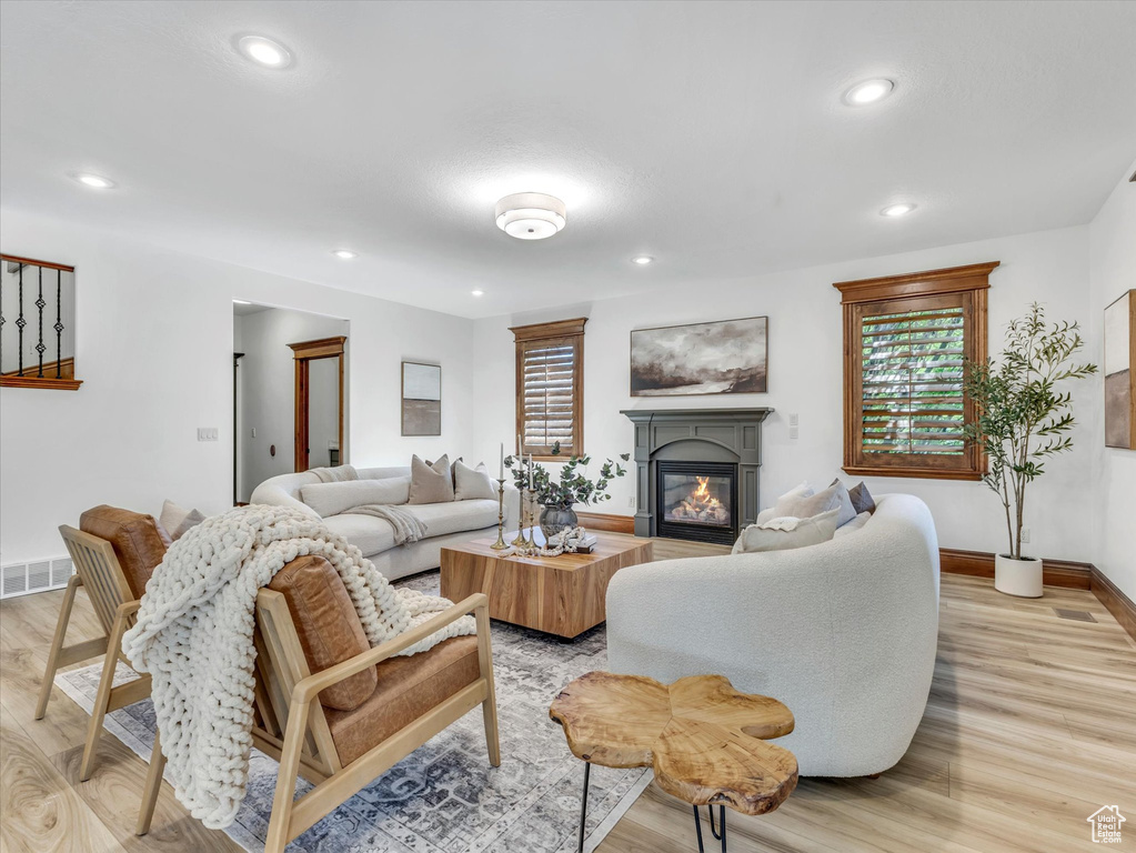 Living room with a glass covered fireplace, light wood-type flooring, and recessed lighting