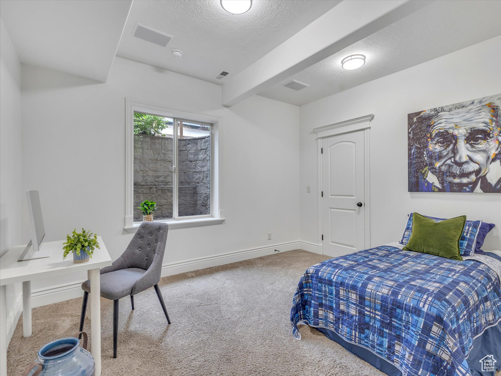 Bedroom with carpet floors, beamed ceiling, and a textured ceiling
