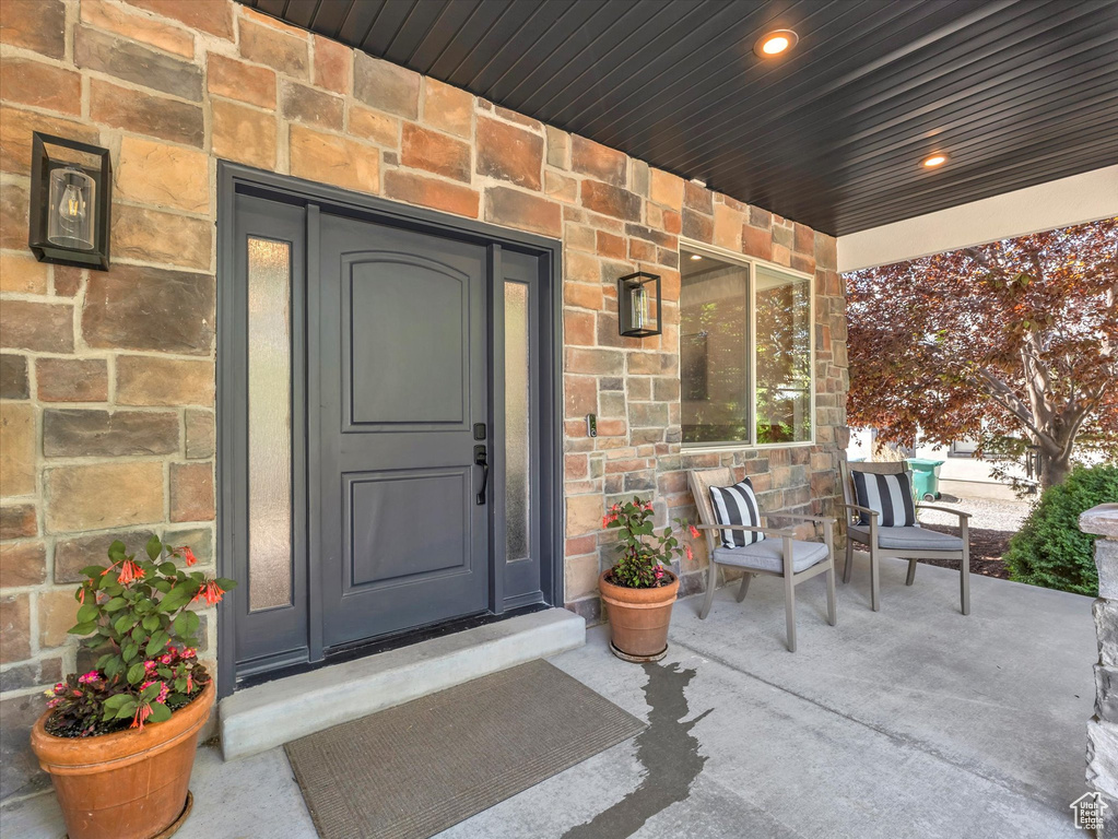Doorway to property featuring covered porch and stone siding