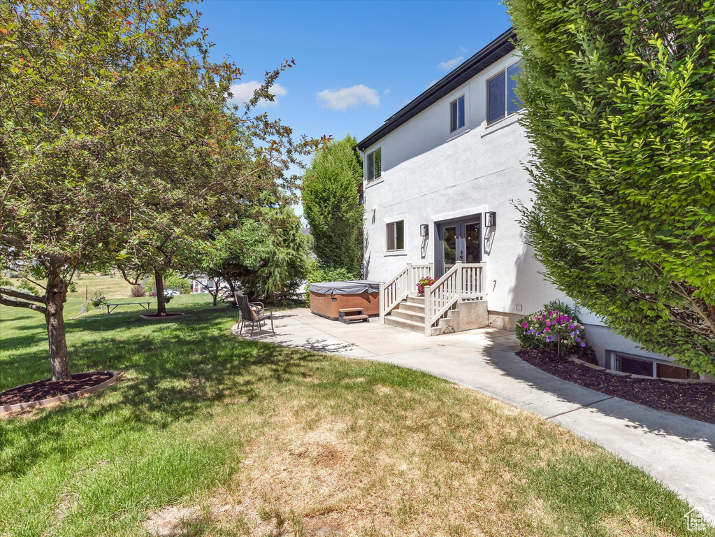View of green lawn featuring a hot tub, french doors, and a patio area