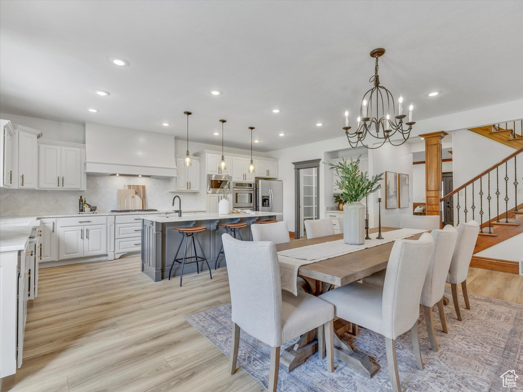 Dining area with light wood-type flooring, a chandelier, stairs, and recessed lighting