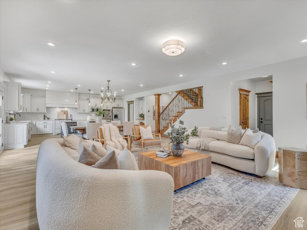 Living area with stairs, recessed lighting, light wood-type flooring, and a chandelier
