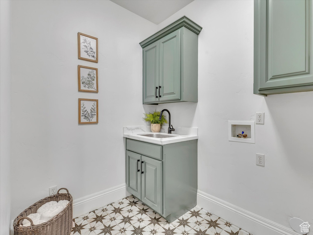 Laundry room with washer hookup, cabinet space, and light floors