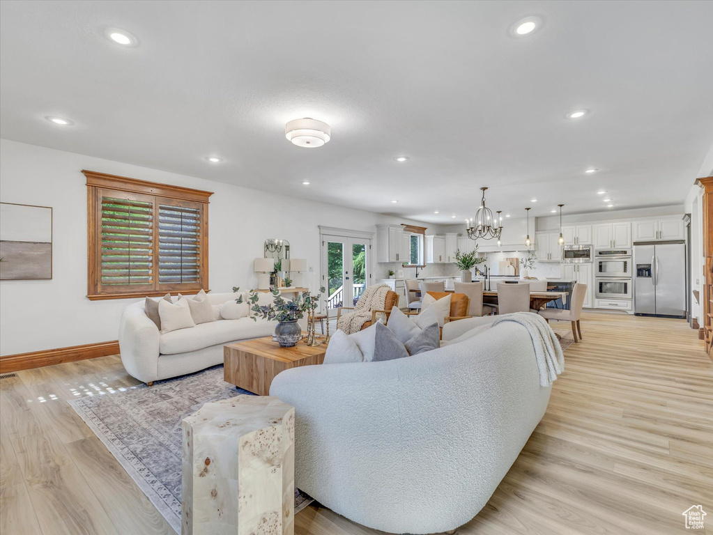 Living area with recessed lighting, light wood finished floors, a chandelier, and french doors
