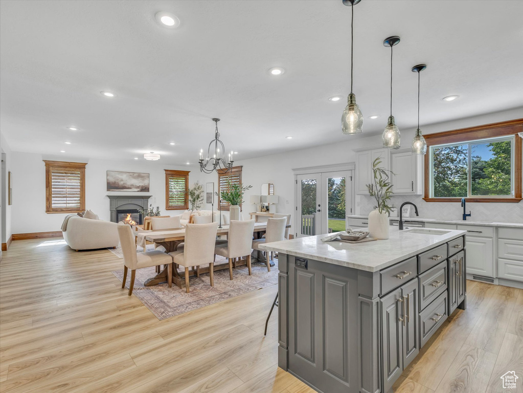 Kitchen featuring gray cabinets, recessed lighting, light wood finished floors, an island with sink, and french doors