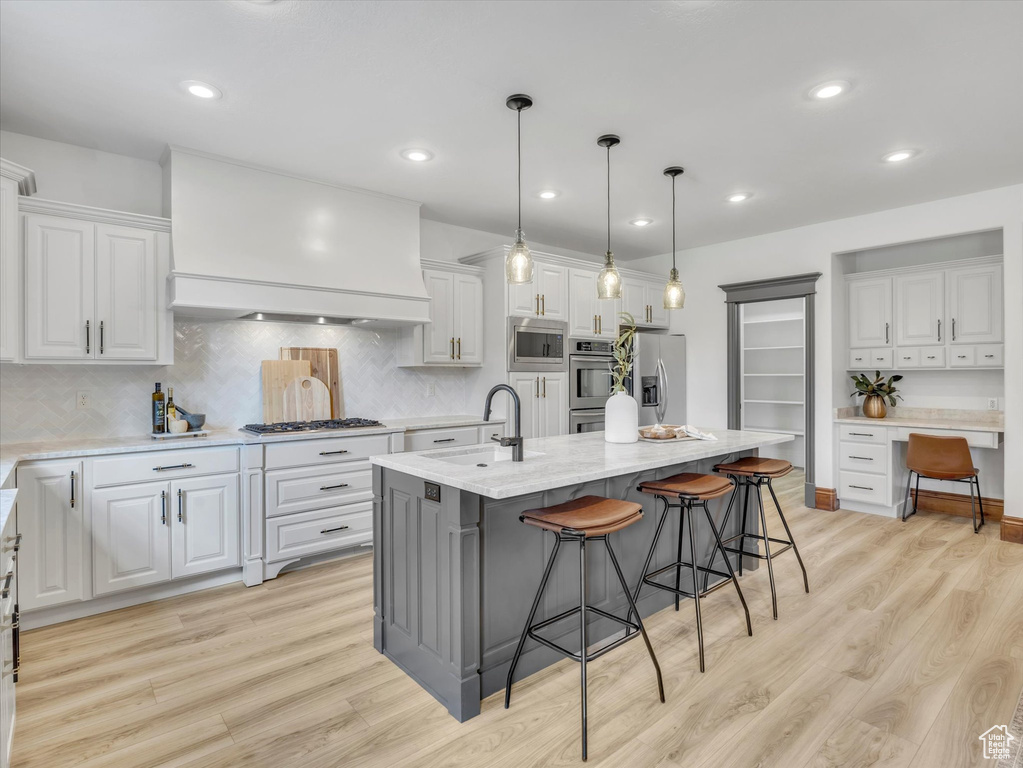 Kitchen featuring appliances with stainless steel finishes, white cabinetry, light wood-type flooring, and recessed lighting