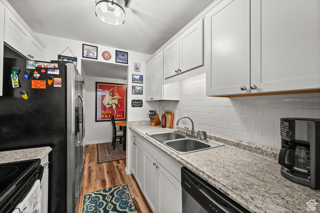 Kitchen featuring light wood-style floors, backsplash, white cabinets, and range with electric stovetop