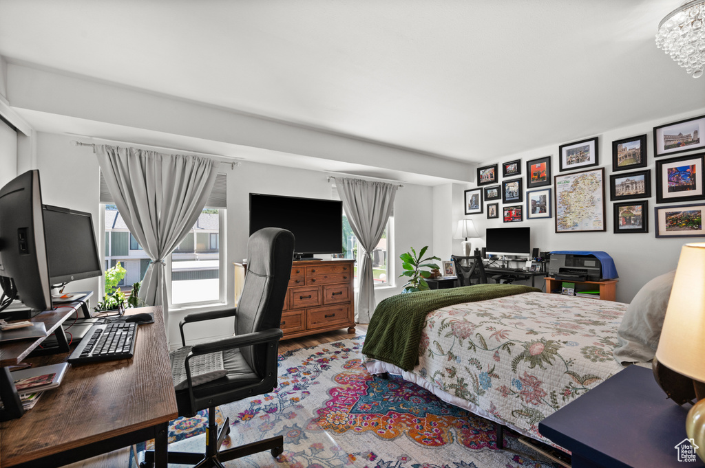 Bedroom featuring a desk, wood finished floors, and a chandelier