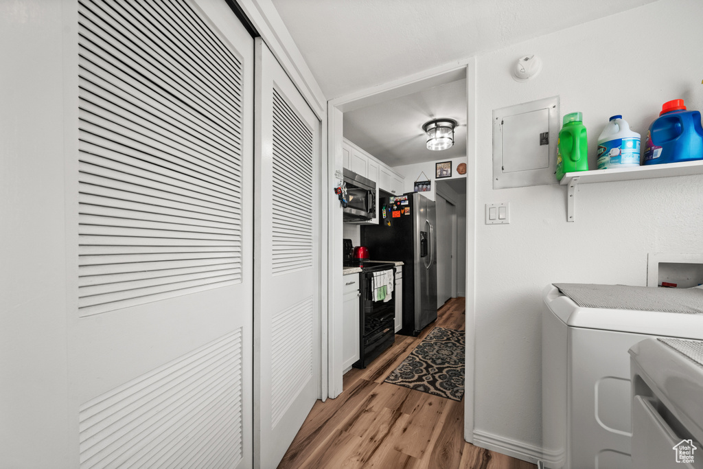 Laundry area featuring electric panel, light wood finished floors, and independent washer and dryer