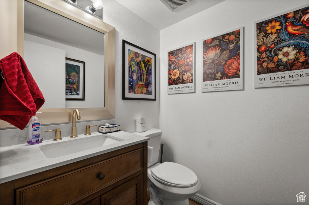 Half bathroom featuring vanity and toilet