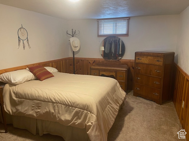 Bedroom with wooden walls, light carpet, and wainscoting