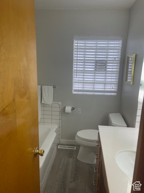 Bathroom with a tub, vanity, and wood finished floors