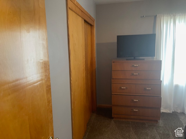 Bedroom with dark colored carpet and a closet