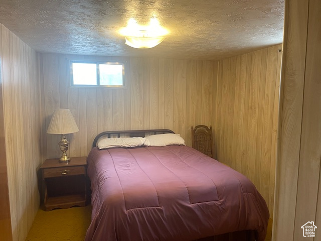 Bedroom with a textured ceiling and wooden walls