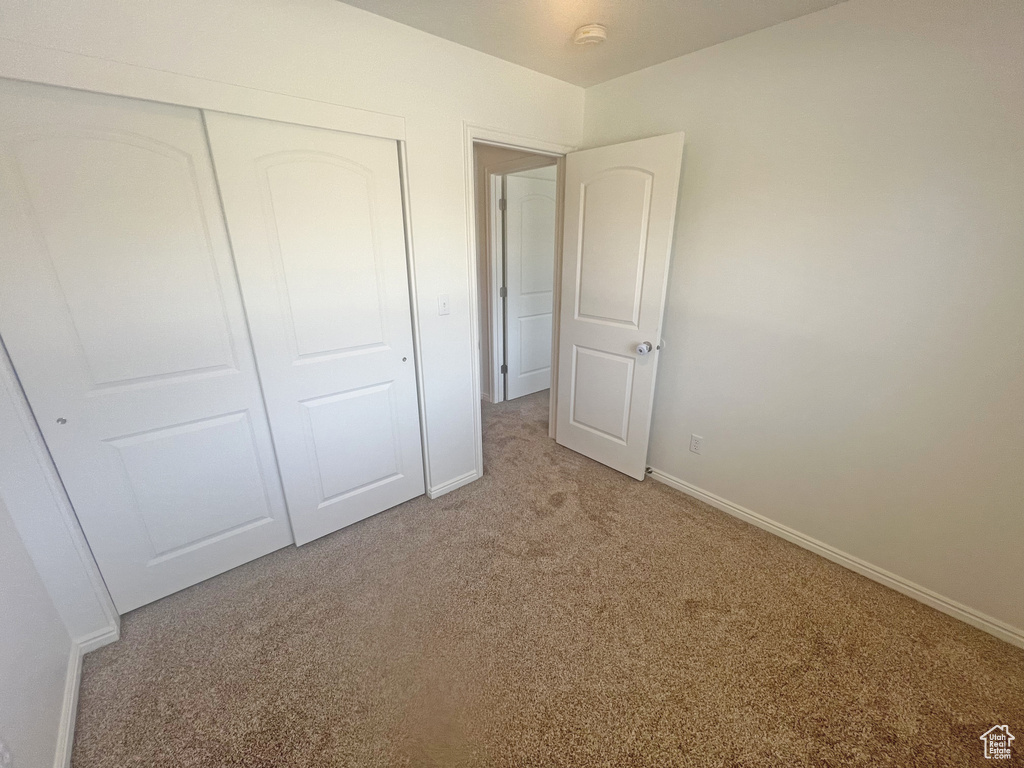 Unfurnished bedroom featuring light colored carpet and a closet