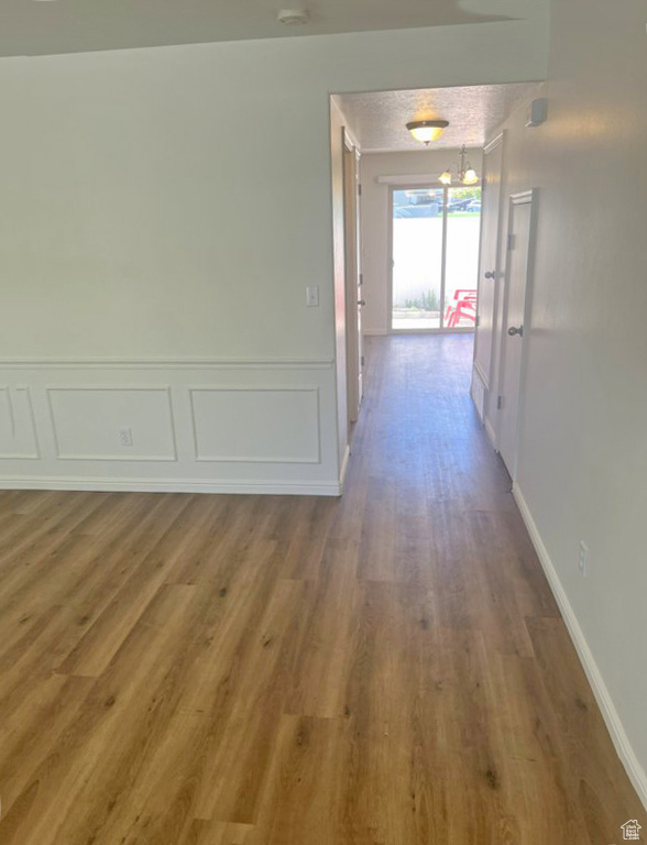 Corridor with wood finished floors, a wainscoted wall, and a decorative wall