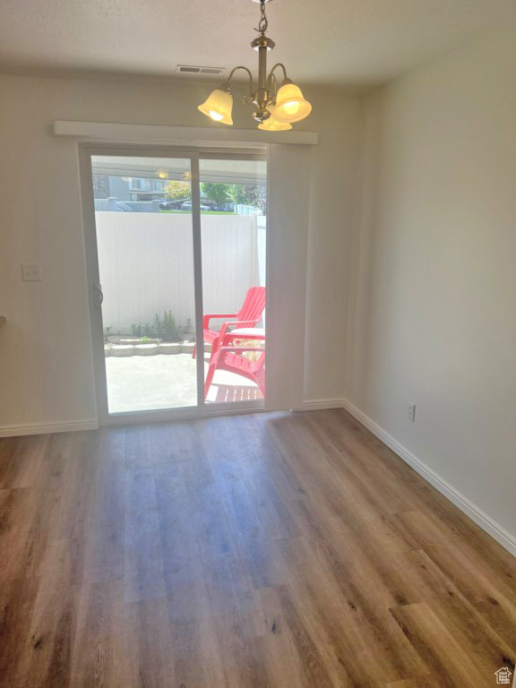 Spare room with wood finished floors and a chandelier