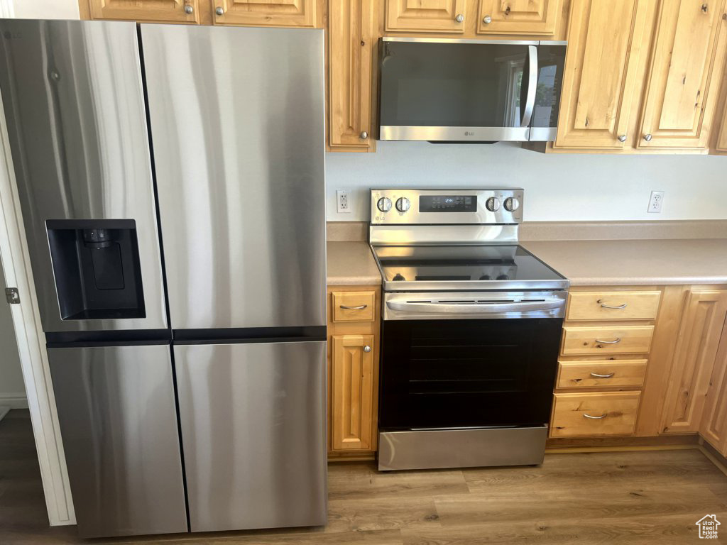 Kitchen with stainless steel appliances, light countertops, and light wood finished floors