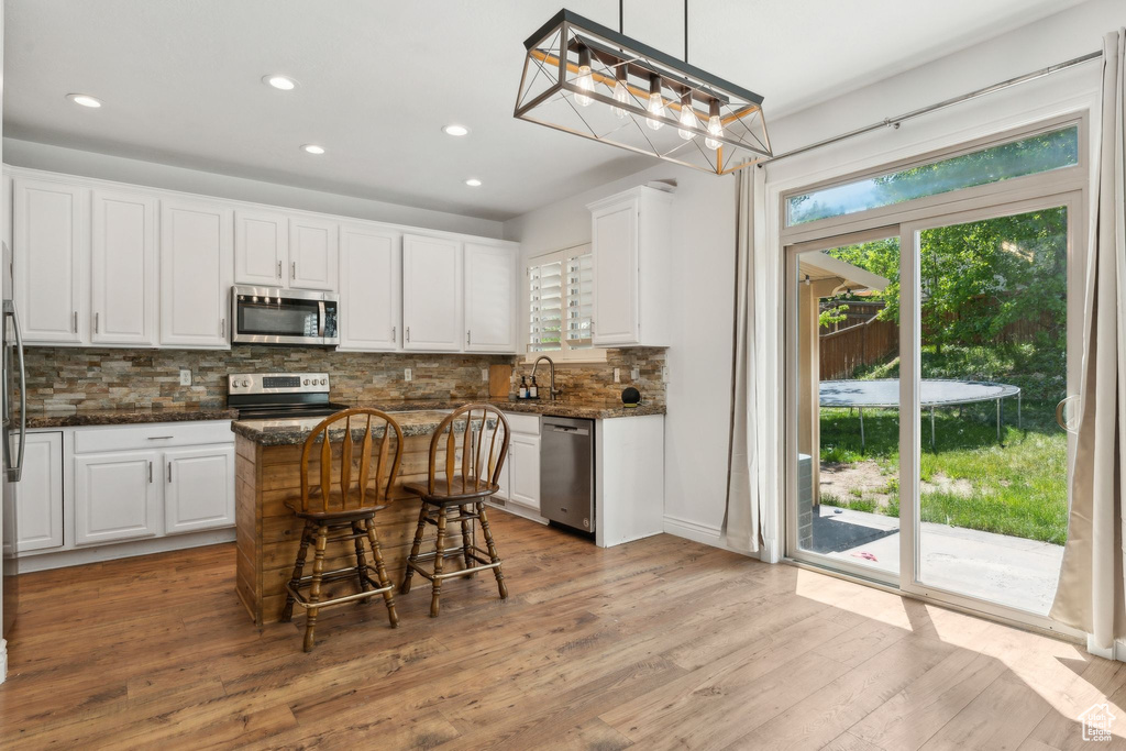 Kitchen featuring appliances with stainless steel finishes, white cabinetry, recessed lighting, backsplash, and light wood finished floors