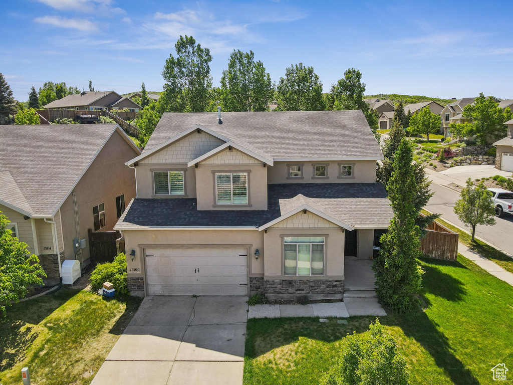 View of front of property featuring stucco siding, stone siding, driveway, and an attached garage