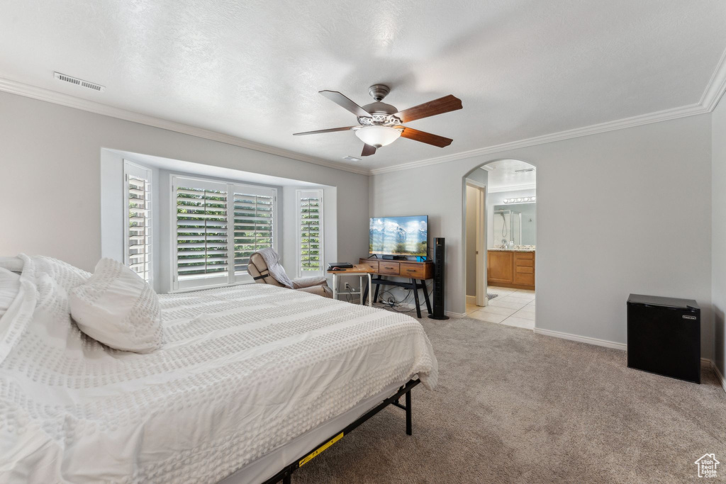 Bedroom featuring ornamental molding, light carpet, baseboards, ceiling fan, and arched walkways