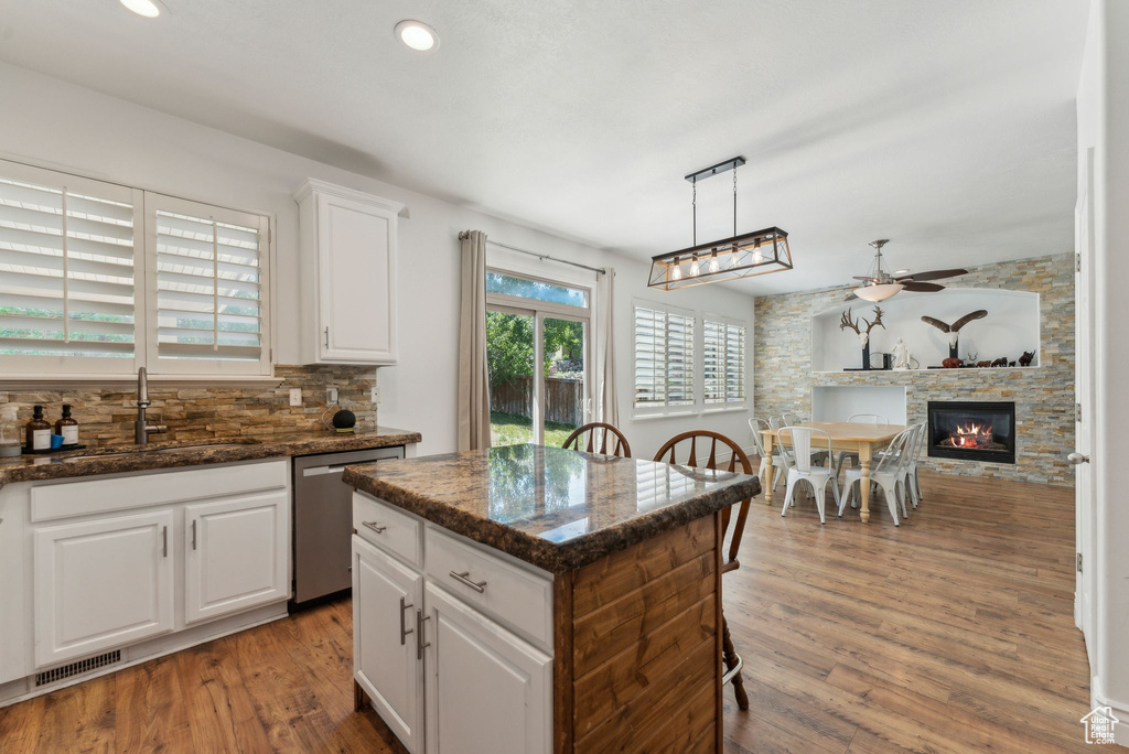 Kitchen with stainless steel dishwasher, a sink, ceiling fan, tasteful backsplash, and light wood finished floors