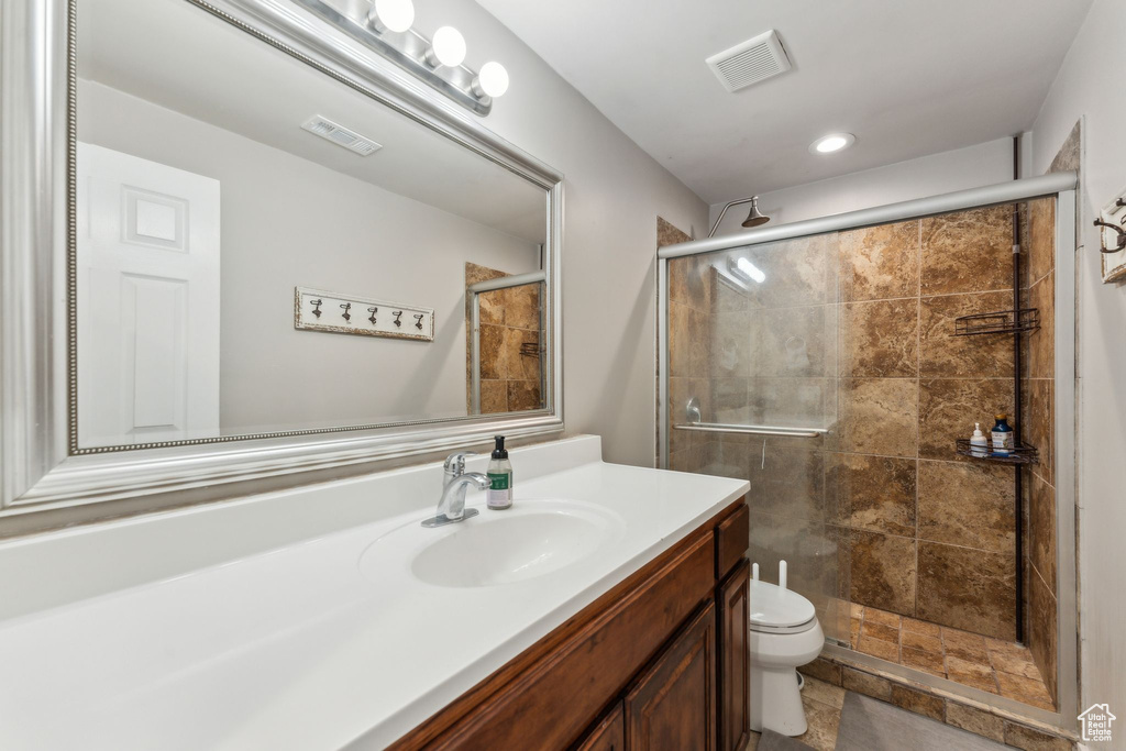 Bathroom featuring vanity, toilet, a stall shower, and recessed lighting