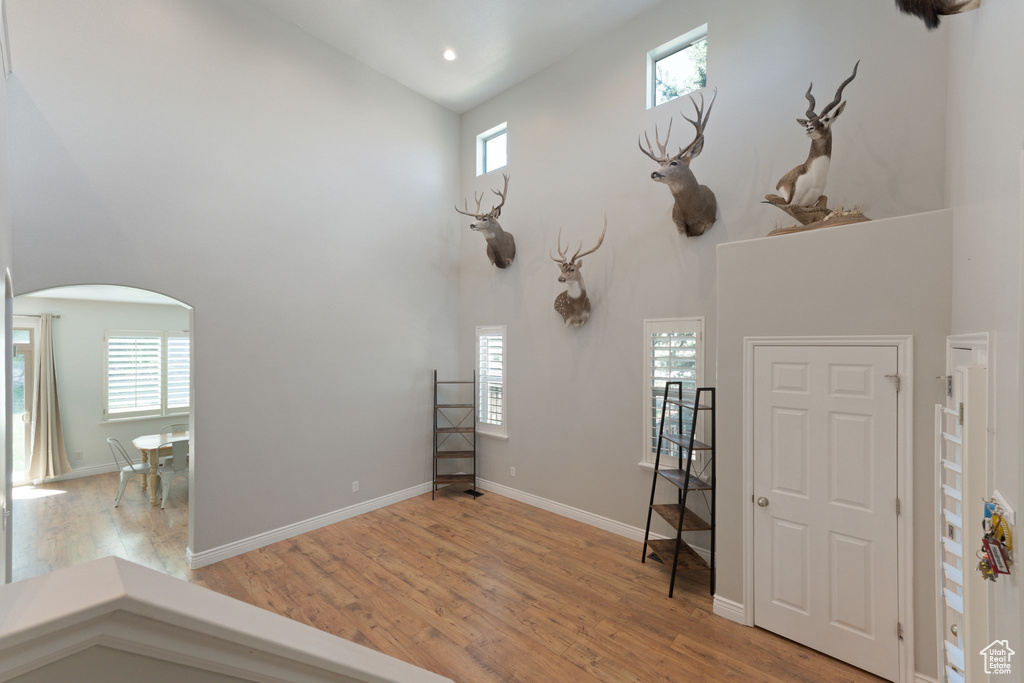 Foyer with a high ceiling, arched walkways, light wood-type flooring, recessed lighting, and baseboards
