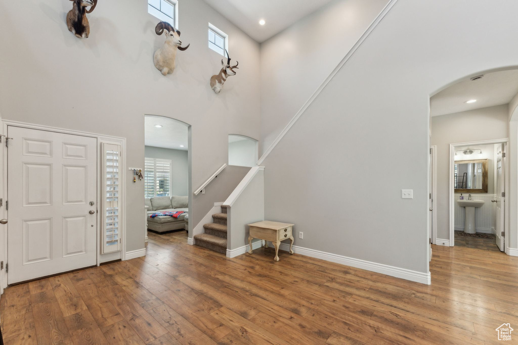 Foyer entrance with arched walkways, hardwood / wood-style floors, a high ceiling, baseboards, and recessed lighting