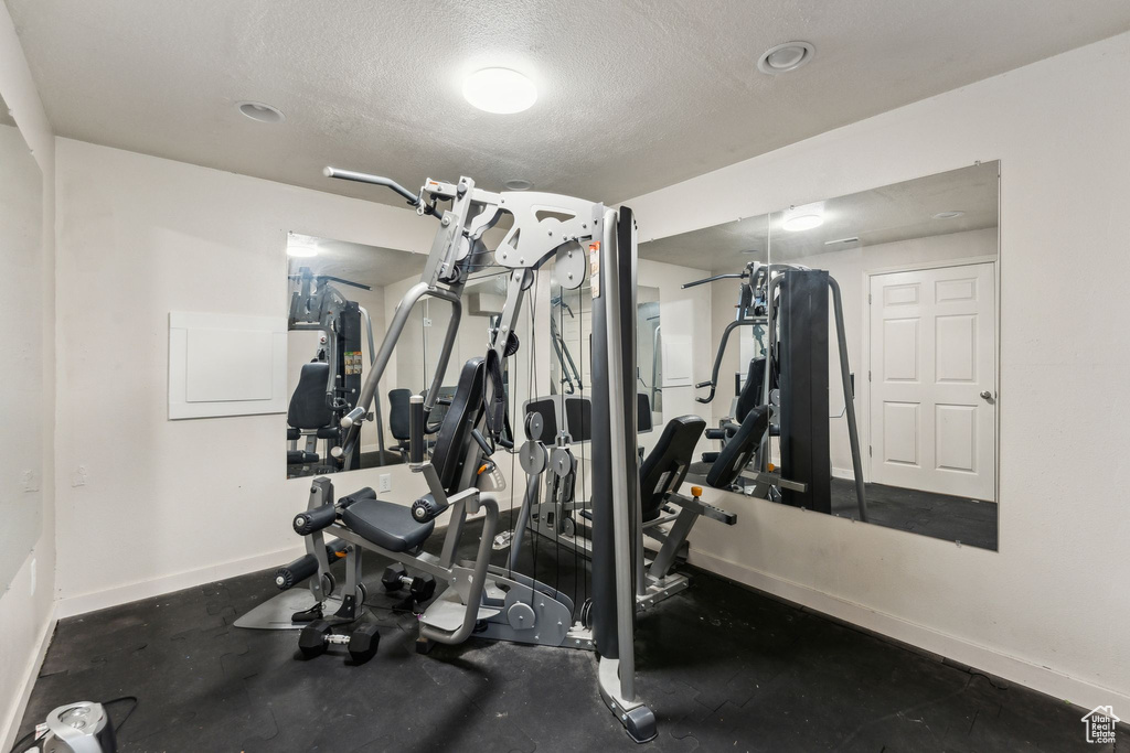Exercise area with baseboards and a textured ceiling