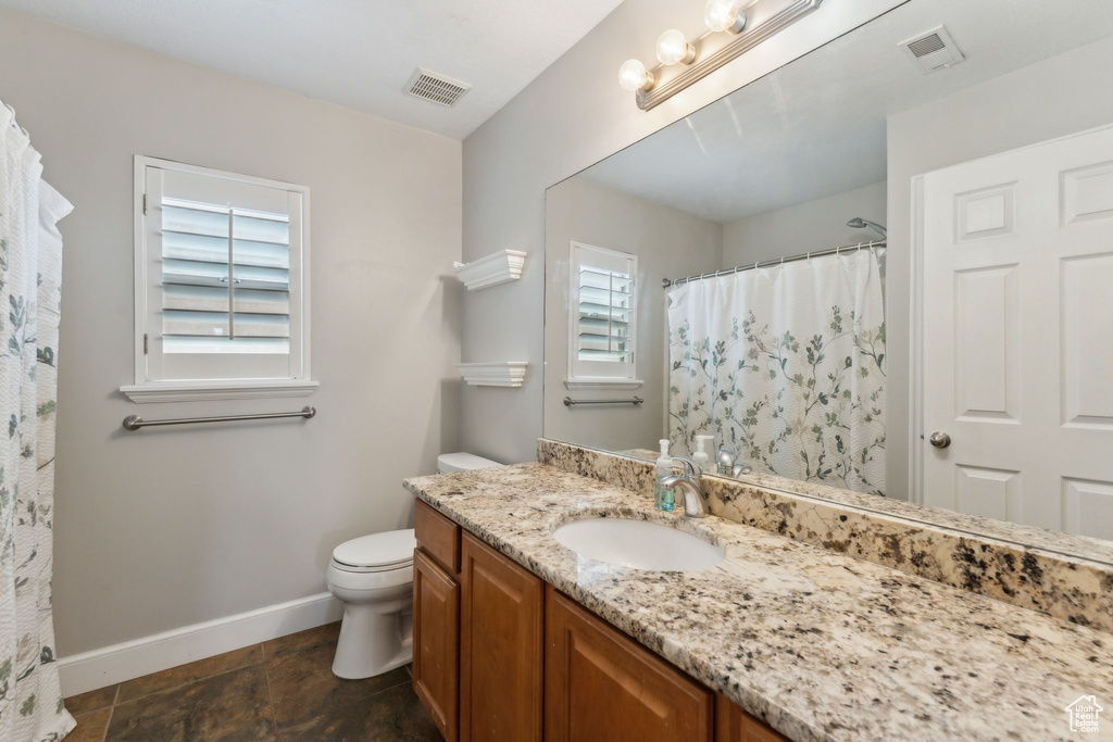Bathroom featuring baseboards, vanity, toilet, and a shower with shower curtain