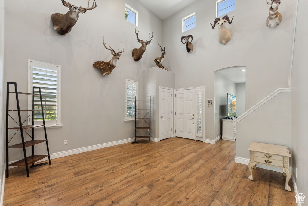 Foyer featuring a towering ceiling, arched walkways, wood finished floors, and baseboards
