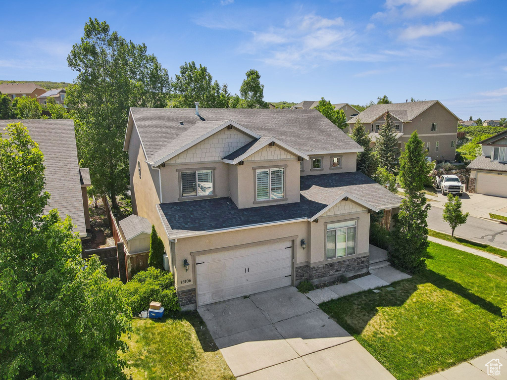 Craftsman house with stone siding, concrete driveway, stucco siding, a garage, and a front lawn