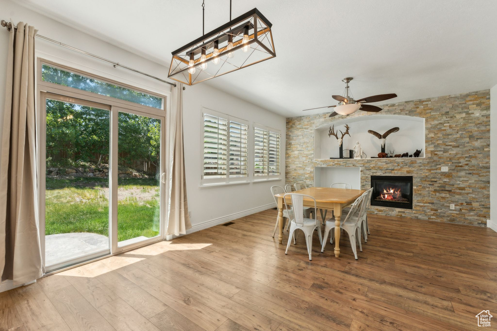 Dining space with ceiling fan, wood-type flooring, plenty of natural light, and a fireplace