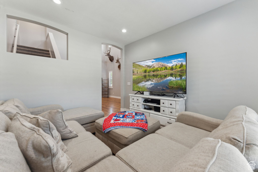 Living room featuring arched walkways, wood finished floors, recessed lighting, and stairs