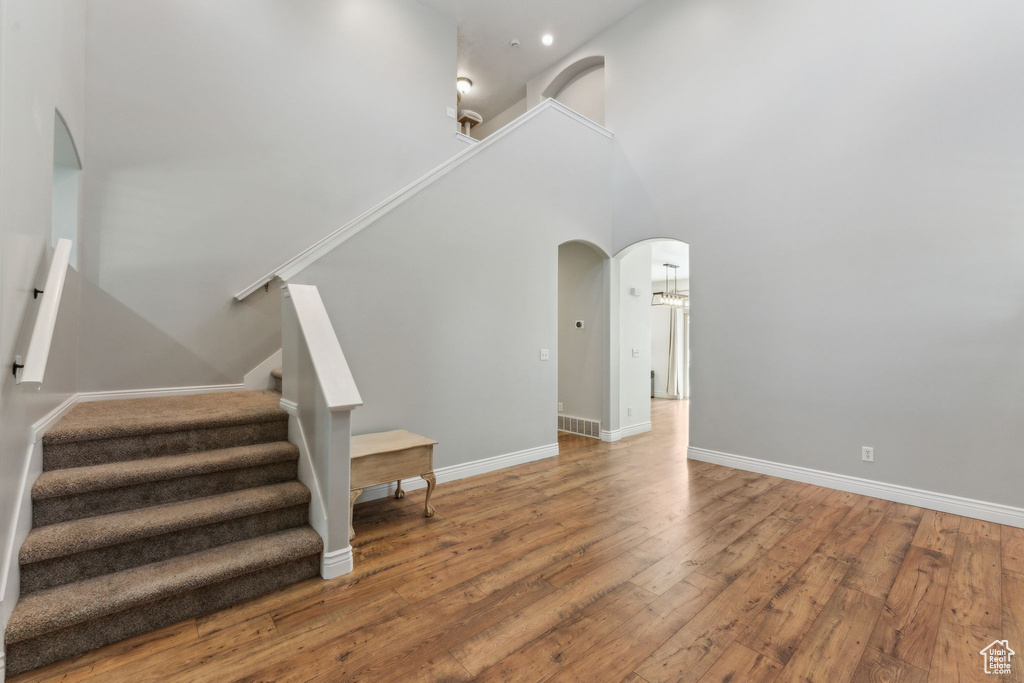 Staircase with a high ceiling, arched walkways, wood finished floors, baseboards, and recessed lighting