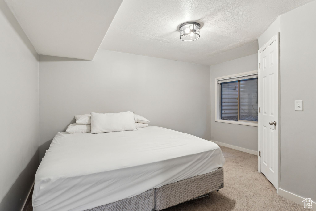 Bedroom with light carpet, baseboards, and a textured ceiling