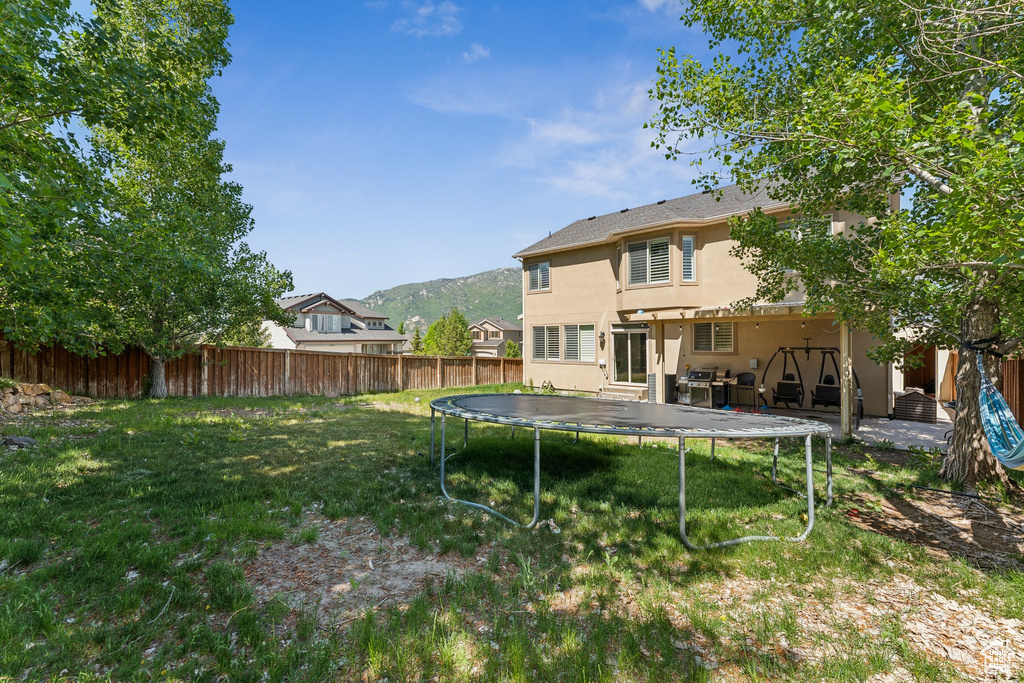 Rear view of house with a trampoline, stucco siding, and a mountain view