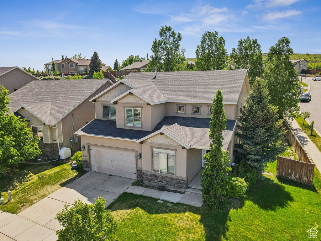 View of front facade with stucco siding, stone siding, a shingled roof, concrete driveway, and a garage