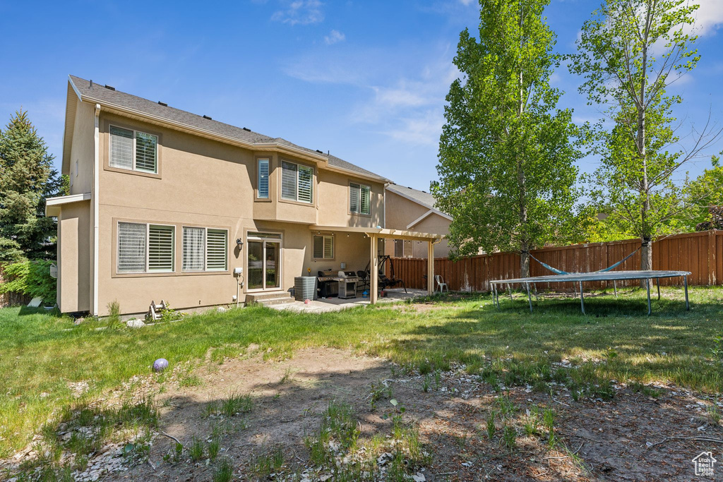 Back of house featuring stucco siding, a trampoline, and a patio area