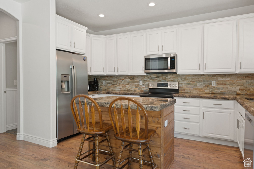 Kitchen featuring stainless steel appliances, white cabinetry, light wood-type flooring, backsplash, and recessed lighting
