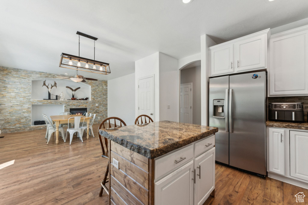 Kitchen featuring stainless steel fridge, arched walkways, wood finished floors, and white cabinets