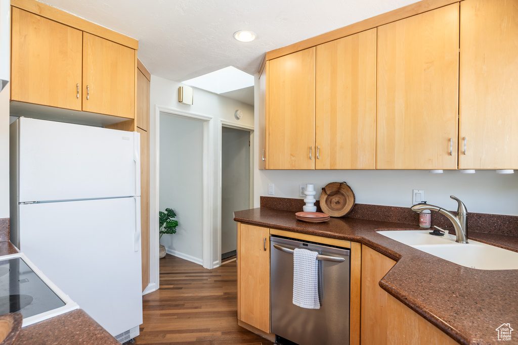 Kitchen featuring stainless steel dishwasher, freestanding refrigerator, light brown cabinets, dark wood-style floors, and recessed lighting